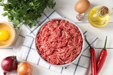 Photo of Raw ground meat in bowl and different products on white wooden table, flat lay