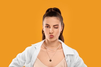 Photo of Beautiful woman with elegant jewelry blowing kiss on orange background