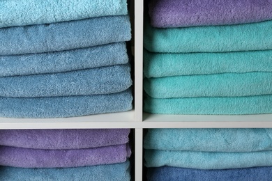 Photo of Colorful towels on shelves, closeup. Bathroom supplies