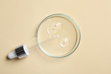 Petri dish with sample of cosmetic oil and pipette on beige background, top view