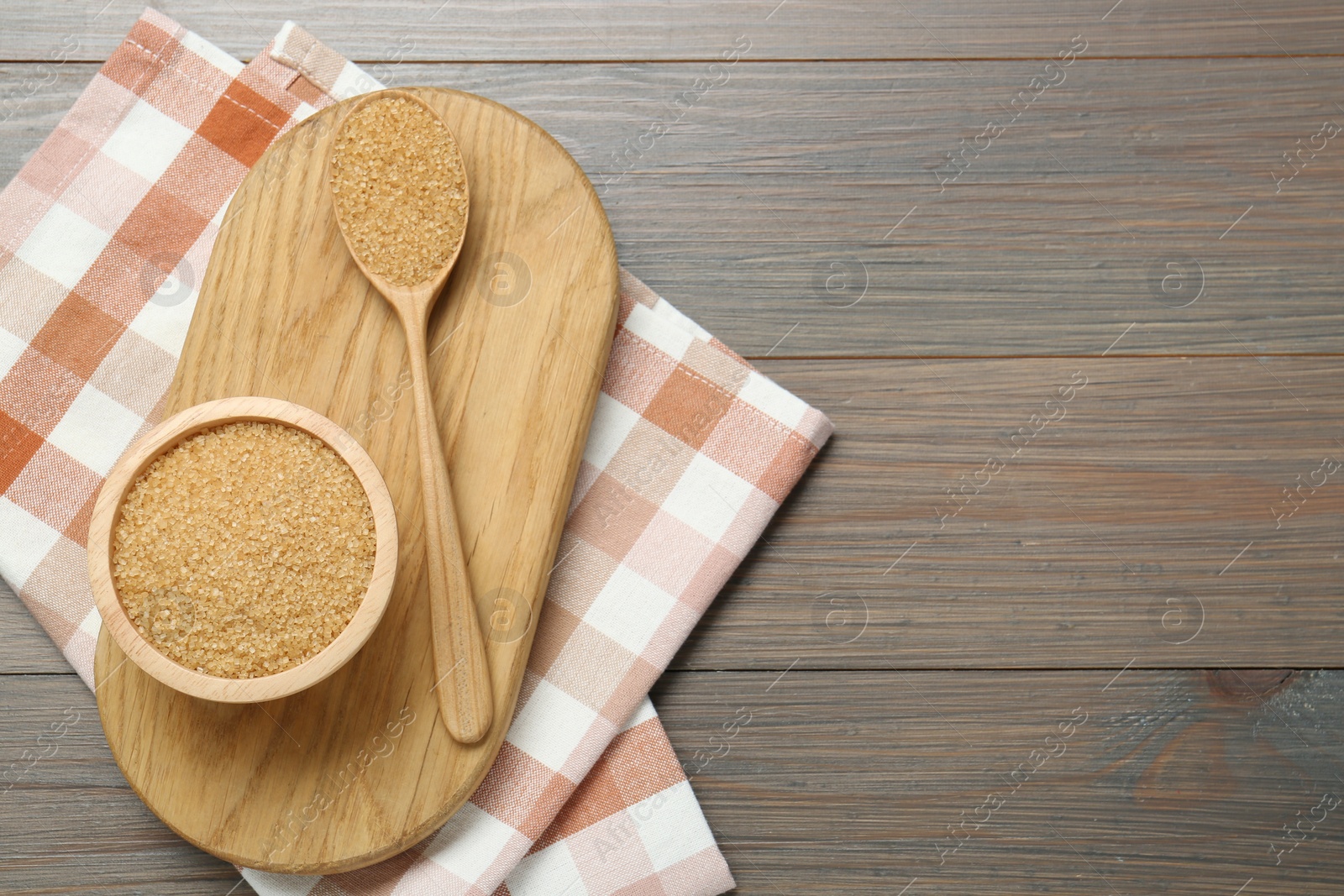 Photo of Brown sugar in bowl and spoon on wooden table, top view. Space for text