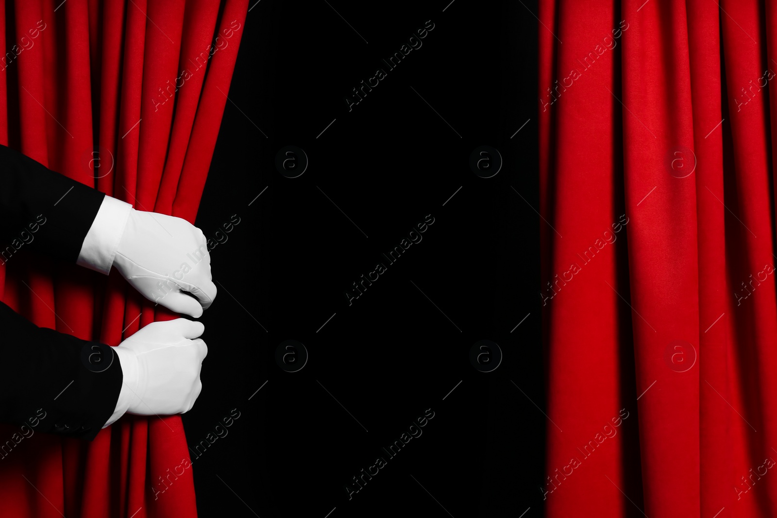 Photo of Person opening red front curtains on black background, closeup. Space for text