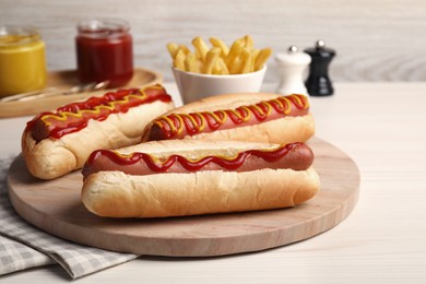 Photo of Fresh delicious hot dogs with sauces on white wooden table