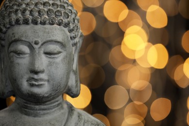 Buddha statue against blurred lights, closeup. Space for text