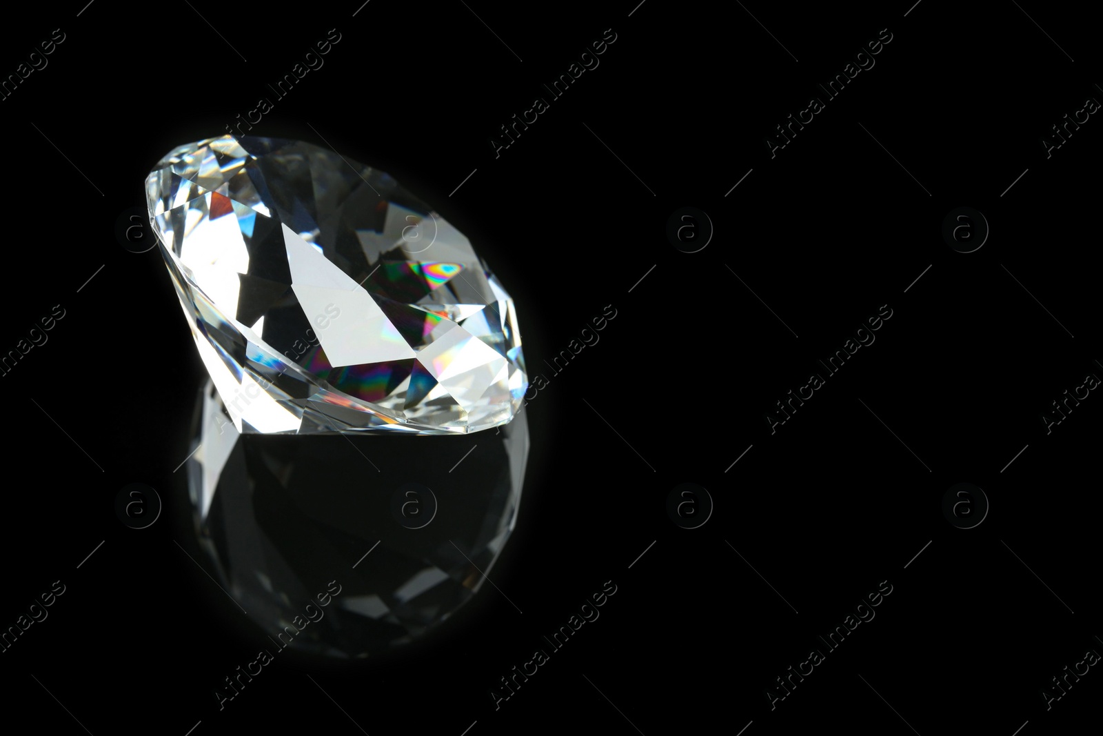 Photo of Beautiful shiny diamond on black mirror surface, closeup. Space for text