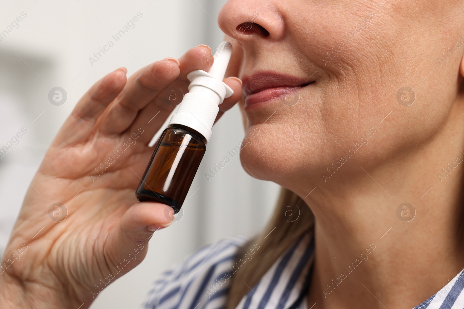 Photo of Medical drops. Woman using nasal spray indoors, closeup