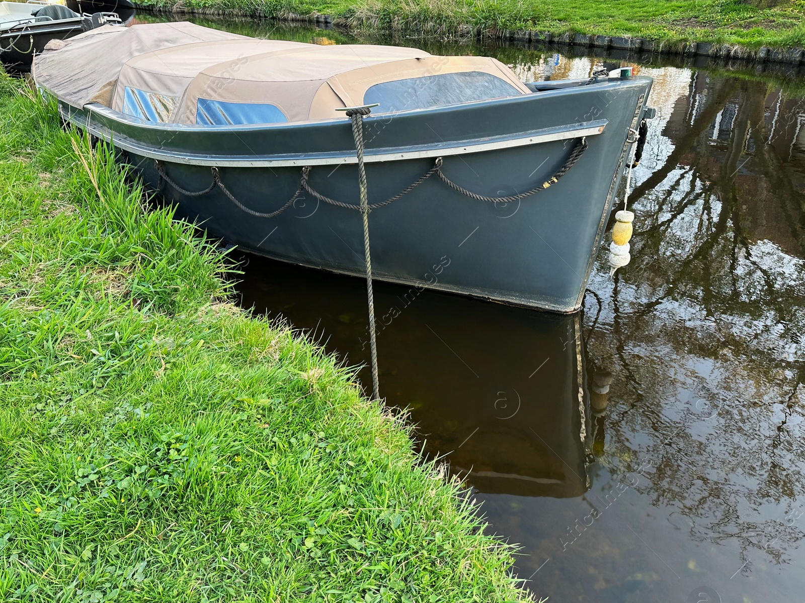 Photo of View of canal with moored boat near green shore