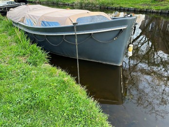 View of canal with moored boat near green shore