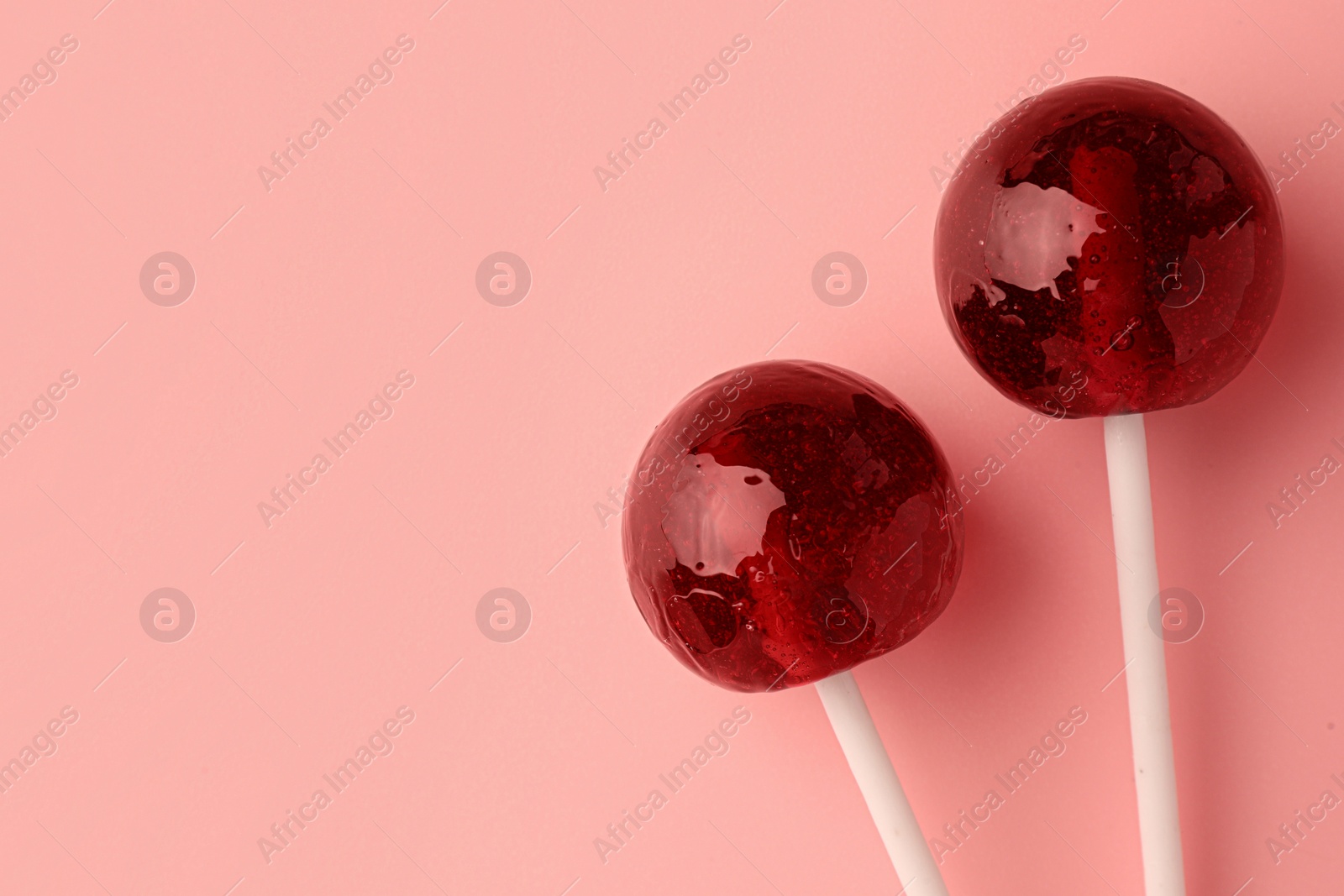 Photo of Tasty lollipops on pink background, flat lay. Space for text