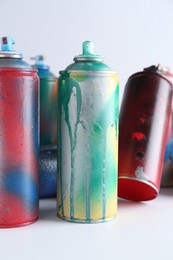 Photo of Many spray paint cans on white background, closeup