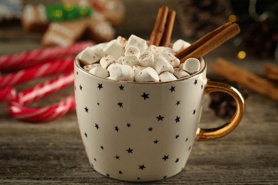 Delicious hot chocolate with marshmallows and cinnamon on wooden table, closeup