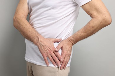 Arthritis symptoms. Man suffering from hip joint pain on gray background, closeup