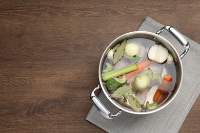 Different ingredients for cooking tasty bouillon in pot on wooden table, top view. Space for text