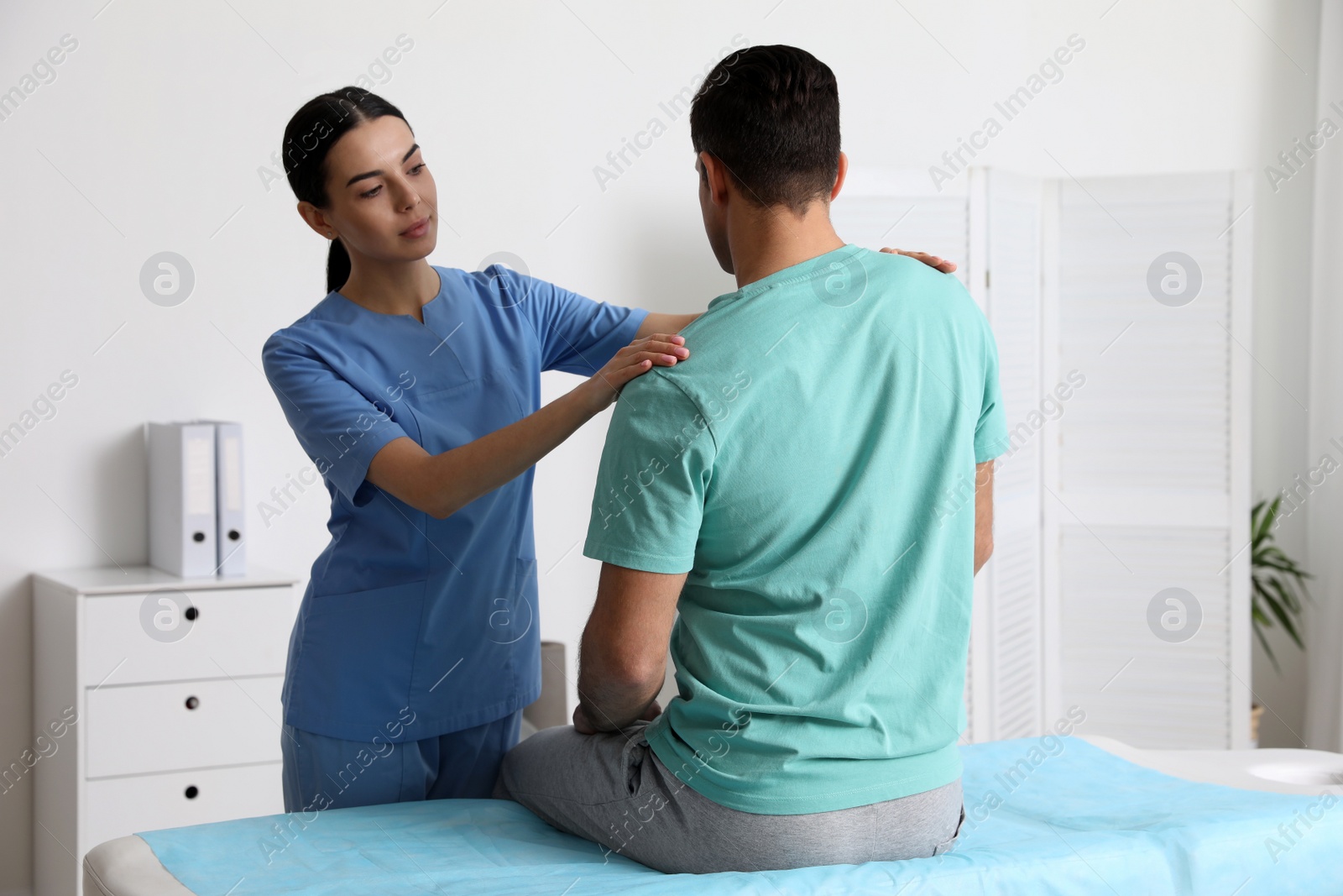 Photo of Orthopedist examining man in clinic. Scoliosis treatment