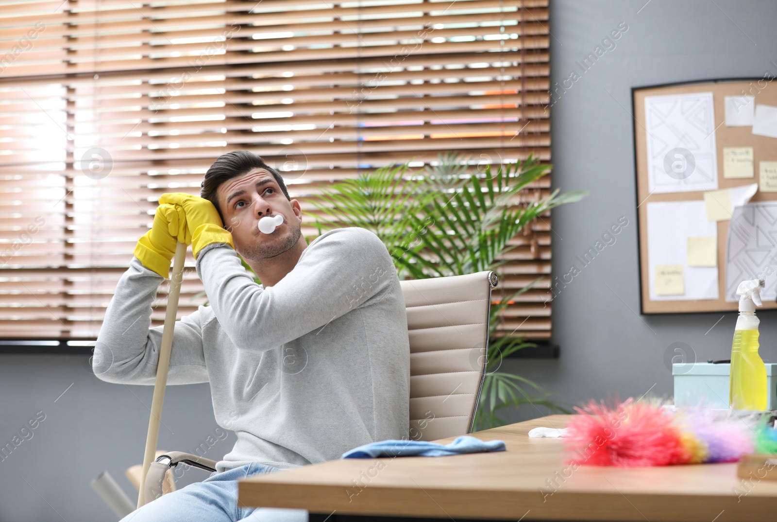 Photo of Lazy man procrastinating while cleaning at home