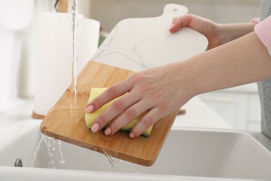 Photo of Woman washing cutting board at sink in kitchen, closeup
