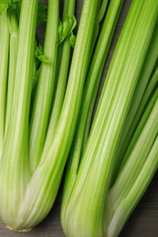 Photo of Fresh green celery stalks on wooden table, top view