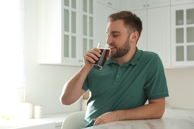 Photo of Handsome man with cold kvass indoors. Traditional Russian summer drink