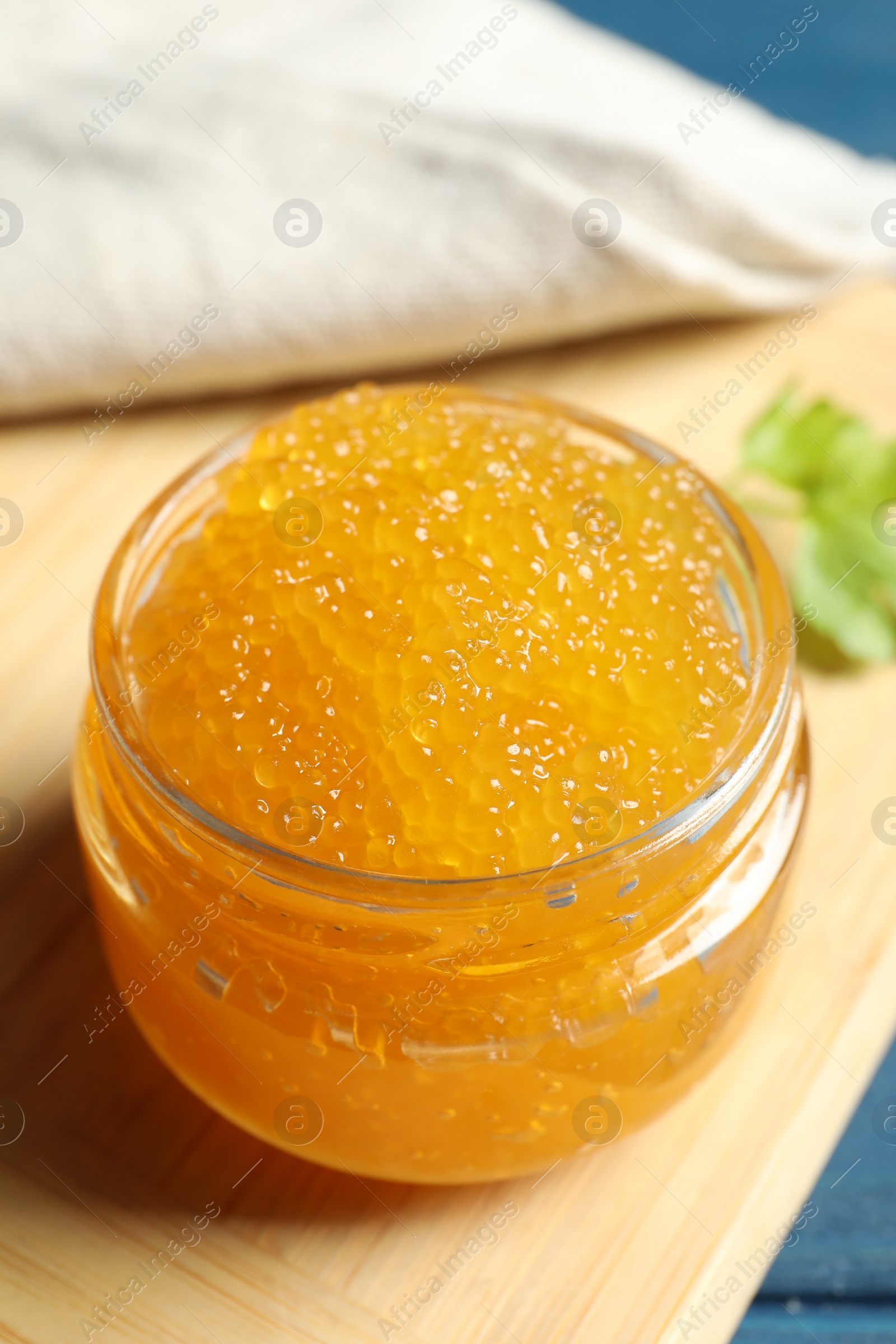 Photo of Fresh pike caviar in glass jar on blue wooden table, closeup