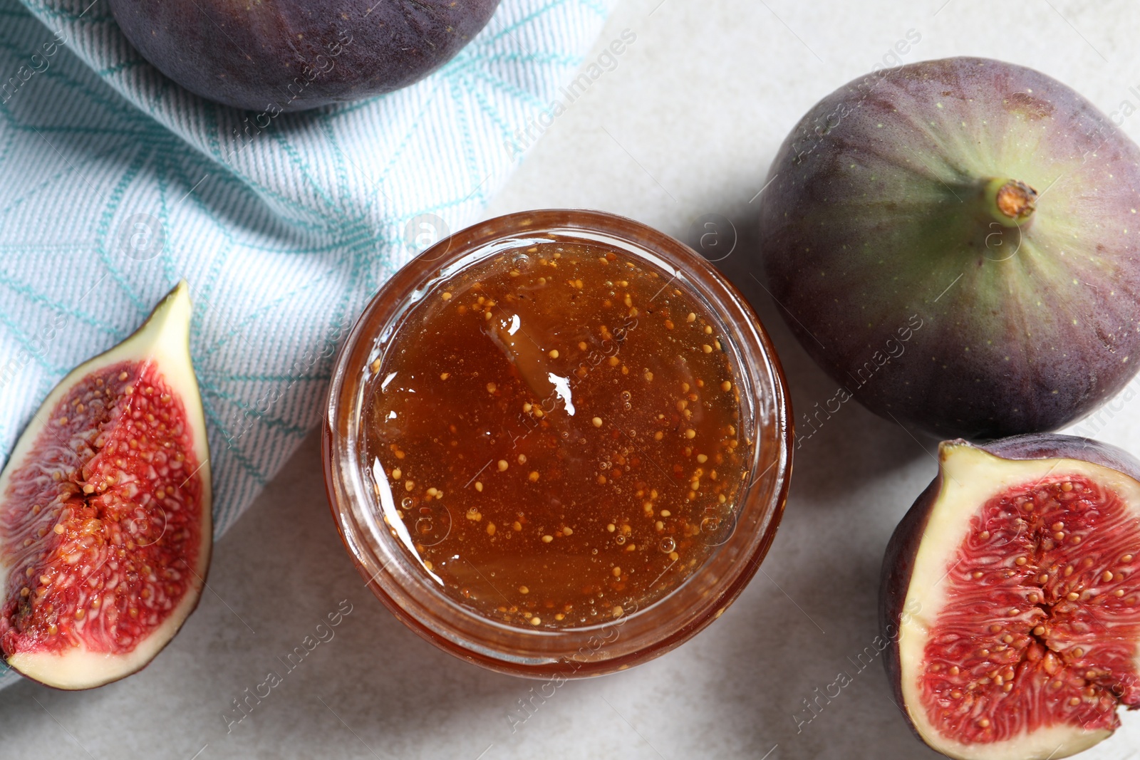 Photo of Jar of tasty sweet jam and fresh figs on light table, flat lay