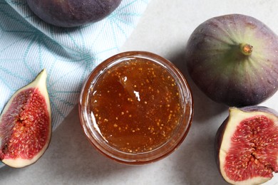 Jar of tasty sweet jam and fresh figs on light table, flat lay