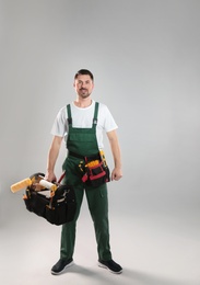 Photo of Full length portrait of professional construction worker with tools on grey background