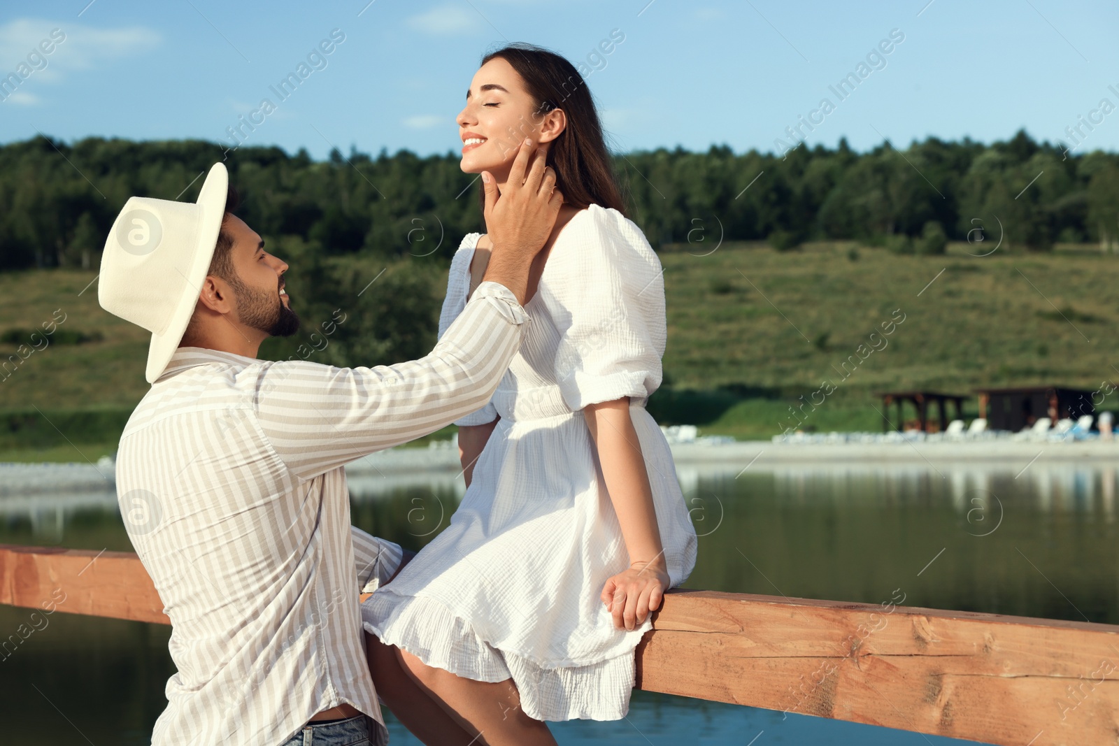 Photo of Romantic date. Beautiful couple spending time together near lake, space for text