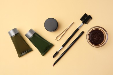 Photo of Flat lay composition with eyebrow henna and tools on beige background