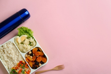 Thermos and lunch box with food on pink background, flat lay. Space for text