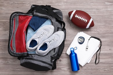 Photo of Grey gym bag and sports equipment on wooden background, flat lay