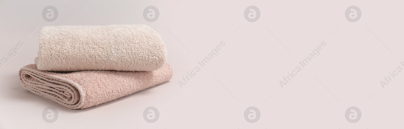 Image of Two folded beige towels on light background, space for text. Banner design