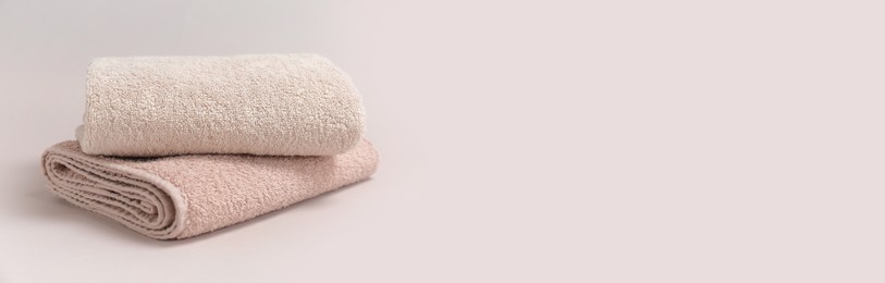 Image of Two folded beige towels on light background, space for text. Banner design