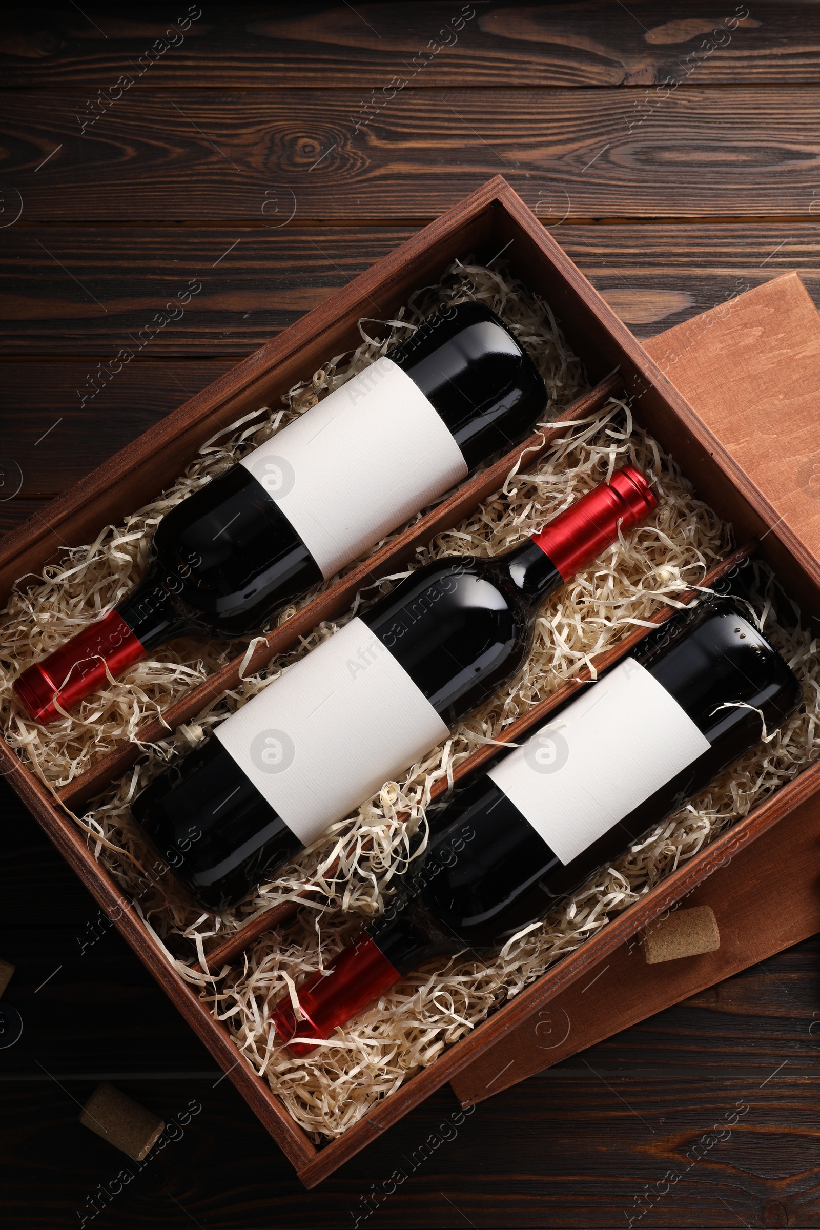 Photo of Box with wine bottles on wooden table, top view