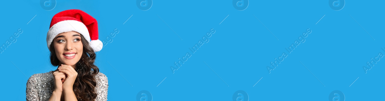 Image of Beautiful woman in Christmas hat on light blue background, space for text. Banner design