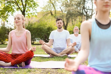 Photo of Grouppeople practicing yoga in park on sunny day