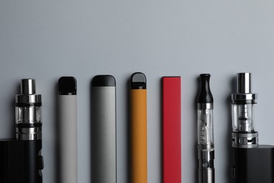 Photo of Many different electronic cigarettes on light background, flat lay