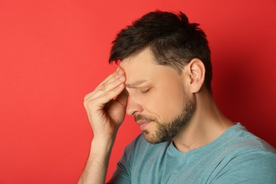 Photo of Man suffering from terrible migraine on red background
