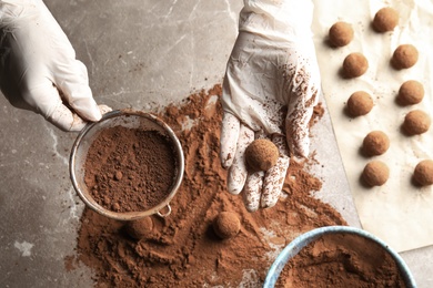 Woman preparing tasty chocolate truffles at table, top view