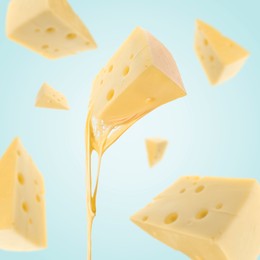 Pieces of cheese falling on light blue background