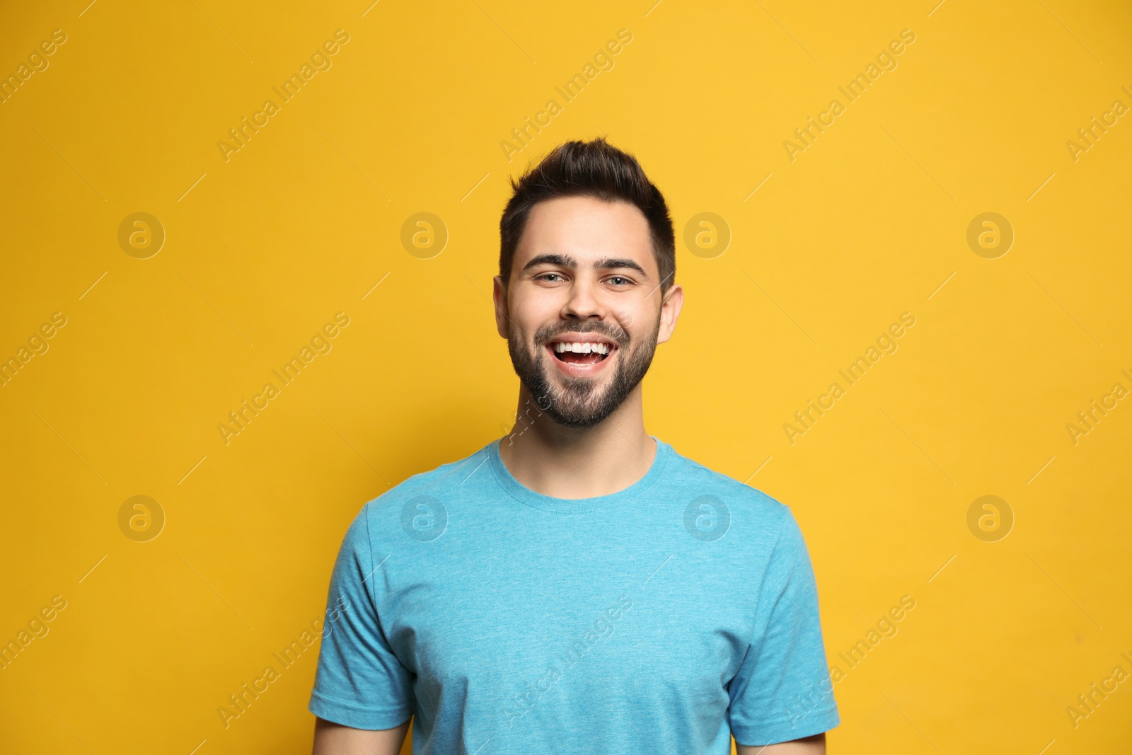 Photo of Young man laughing on yellow background. Funny joke