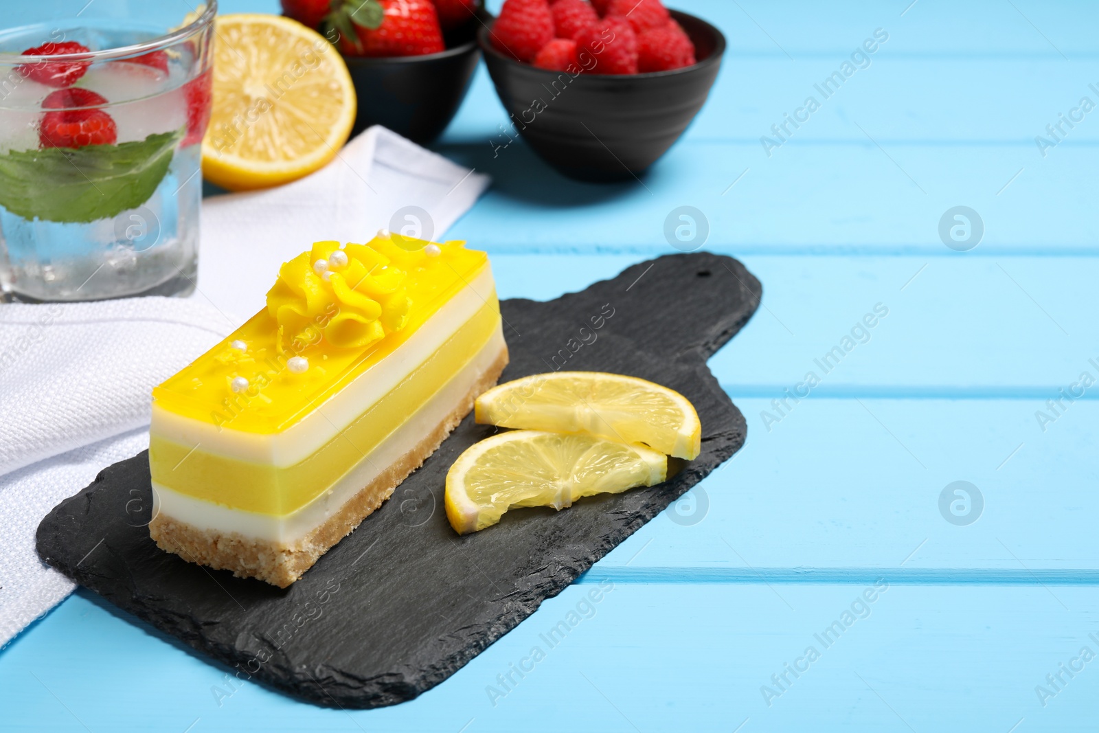 Photo of Delicious cheesecake with lemon on light blue wooden table. Space for text