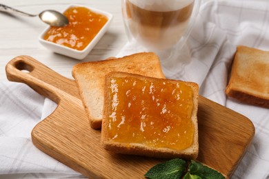 Toast with tasty orange jam, roasted slice of bread and mint on table, closeup