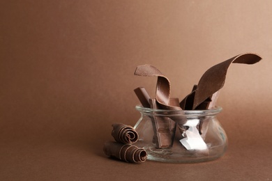 Glass jar with chocolate bars and curls on color background. Space for text