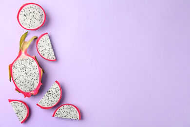 Photo of Delicious cut dragon fruit (pitahaya) on violet background, flat lay. Space for text