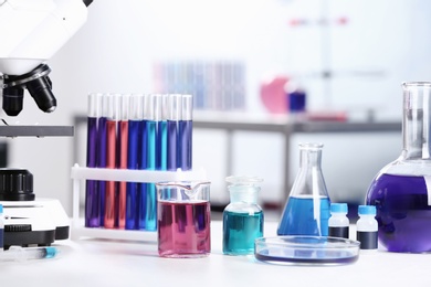 Different glassware with samples and microscope on table in chemistry laboratory