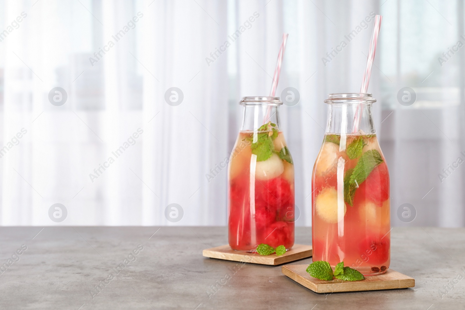 Photo of Bottles with tasty watermelon and melon ball drink on table. Space for text