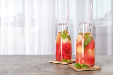 Bottles with tasty watermelon and melon ball drink on table. Space for text