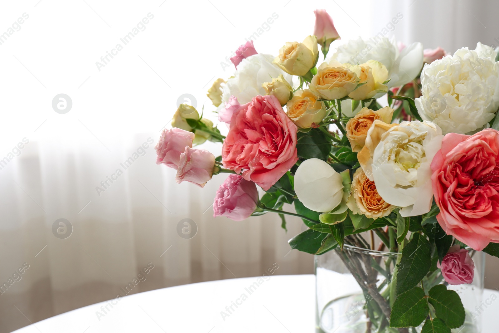 Photo of Beautiful flower bouquet in vase on table near window at home. Space for text