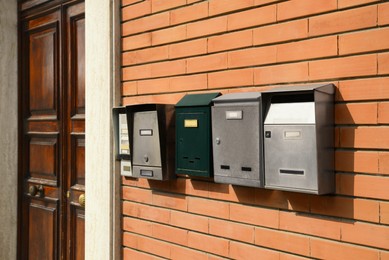 Photo of Many different mailboxes on red brick wall of building