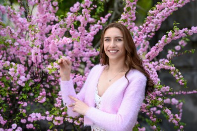 Photo of Beautiful young woman near blossoming sakura tree on spring day